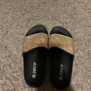 Black sandals with gold rhinestones on it.